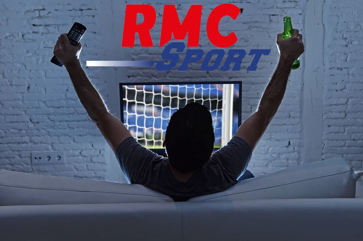 Homme lève les bras en signe de victoire devant sa télé car RMC Sports est en promo