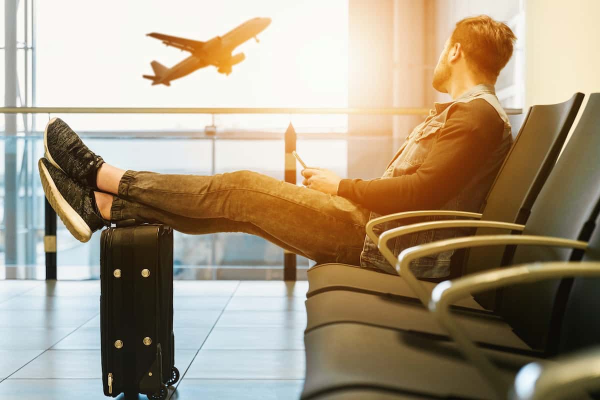 Homme en salle d'attente de l'aéroport, content avec le forfait 200 Go de Bouygues Telecom idéal pour les voyageurs