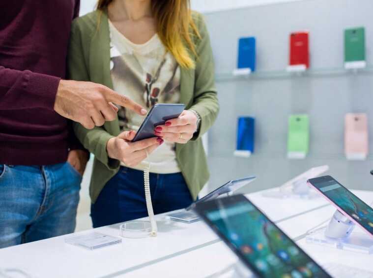 Deux personnes examinent un smartphone dans un magasin.