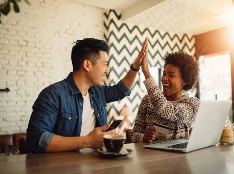Un homme et une femme font un check devant un ordinateur portable et une carte bancaire dans un café.