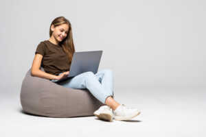 Femme sur son pouf avec PC, contente de son abonnement Box