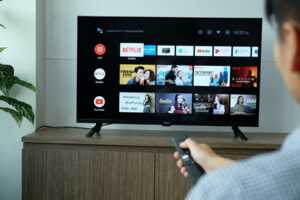 Homme zappe devant son téléviseur avec applications, devenu smart TV grâce à un décodeur Android