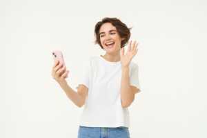Jeune femme en jean sourit à son smartphone car elle n'a plus besoin ni envie de Box Internet