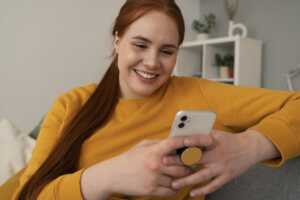 Fille sourit avec son smartphone, tranquille, grâce à la sécurisation des données incluse avec les forfaits Bouygues Telecom
