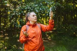 Femme lève bras pour chercher réseau en forêt