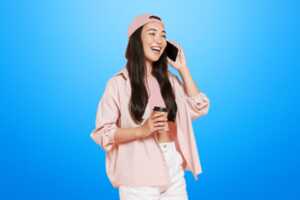 Femme avec smartphone et café sur fond bleu sourit, heureuse de son forfait de 350 Go à 8€ chez Lebara