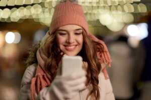 Femme à bonnet sourit à son Galaxy S23 FE, en super promo chez Rakuten