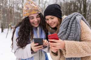 2 amies dehors en hiver avec smartphones, comparent leurs forfaits mobile chez RED by SFR et B&YOU