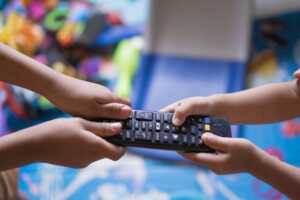 Des mains se battent pour une télécommande, ce qui sera évité avec le 2eme décodeur TV fourni dans les abonnements Premium d'Orange et SFR