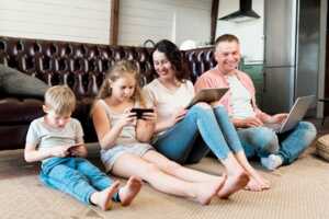 Toute la famille avec écrans sur canapé car la Bbox est offertes avec les économies de B.iG