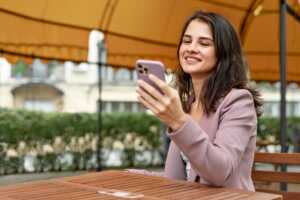 Femme en terrasse avec smartphone ravie de son Xiaomi Redmi Note 14 4G pas cher sur Amazon