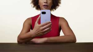 Femme en débardeur rouge tient le Google Pixel 9a, en promo sur Amazon
