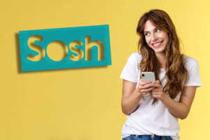 Femme sur fond jaune, sourit avec smartphone à la main, contente de son forfait Sosh