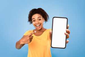 Femme sur fond bleu montre son smartphone, ravie de son forfait YouPrice à moins de 10€ sur réseau Orange