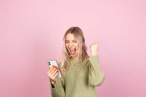 Femme serre poing de joie en regardant son smartphone, ravie de son forfait Lebara avec 250Go de 5G à moins de 9€