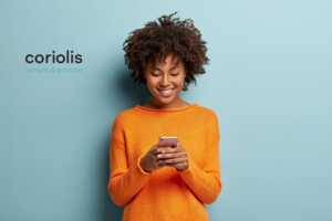 Femme sourit avec son smartphone et son nouveau forfait Coriolis, simple et proche