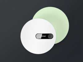 Boîtier Freebox blanc de forme circulaire avec écran central, sur fond gris foncé et cercle vert clair.
