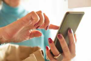 Main de femme scrolle sur smarpthone, car le Galaxy S22 de Samsung, à 200€ chez Rakuten