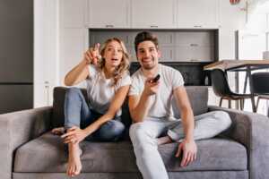 Couple sur canapé avec télécommande, regarde la TV sans Box grâce à Molotov