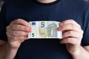 Homme tient un billet de 5€, le prix d'une tablette avec une offre Box + High-Tech de SFR