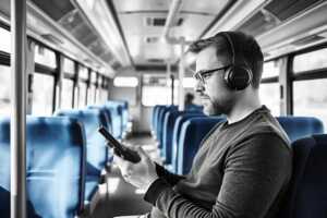 Homme avec casque audio et smartphone streame dans un bus via son forfait mobile Free ou SFR