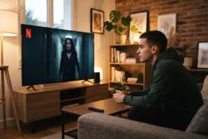 Un jeune homme assis devant une télévision diffusant une série thriller sur Netflix.