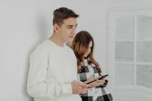 2 ados contre un mur avec smartphone, bien équipés avec forfait mobile "SaferPhone" d'Orange