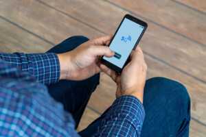 Mains d'homme tiennent un smartphone en 5G, car forfait le moins cher à 6.99€ seulement chez YouPrice sur réseau SFR