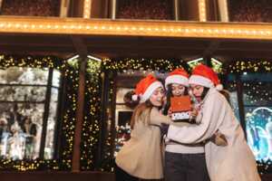 3 Filles avec bonnet de Père Noël ouvrent un cadeau dans la rue, ravies de découvrir 80 Go à 6.99€ et 4 mois de Deezer gratuit grâce à RED by SFR