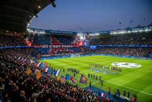 Vue du Parc des Princes rempli de supporters lors d'un match PSG contre Barcelone sous les projecteurs.