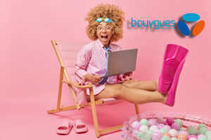 Fille sur fond rose avec palmes et PC, ravie de la fibre pas chère de Bouygues Telecom