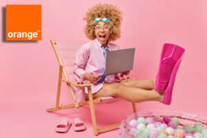Fille sur fond rose avec PC et palmes et logo d'Orange, super heureuse d'avoir la fibre à moins de 20€