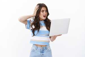 Femme tient PC portable avec main sur la tête et bouche ouverte de surprise et horrifiée, car a oublié qu'avec le combo Box+mobile, on peut économiser 5 à 7€ chez Orange et Bouygues Telecom