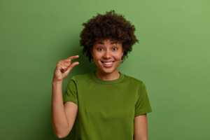 Fille sur fond vert, avec 2 doigts rapprochés pour symboliser les petits prix d'Auchan Telecom