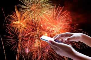 Main tient smartphone et feu d'artifice sur fond noir, car explosion de bonheur avec le forfait 150 Go de Sosh à 10€