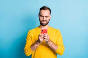 Homme avec smartphone pas content, car il est dysfonctionnel, comme celui de 40% des Français