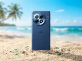 Smartphone OnePlus bleu posé sur le sable d'une plage avec des palmiers en arrière-plan.