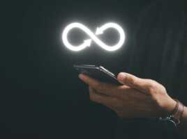 Main tient smartphone sur fond noir avec symbole de l'infini au-dessus, car forfait à data illimitée chez NRJ Mobile pour seulement 17.49€