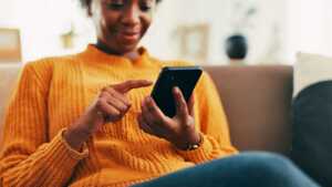Homme scrolle sur son smartphone en souriant, ravi de l'application Cafeyn offerte pour 6 mois avec son forfait mobile de Bouygues Telecom