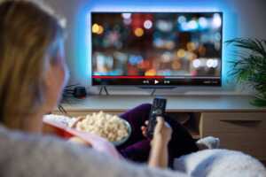 Femme dans canapé avec popcorn, devant la SVoD de sa télé à 1€ l'abonnement grâce à sa Livebox Max