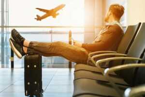 Homme attend à l'aéroport, prêt à voyager avec le pack séjour de SFR pour son smartphone