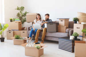 Couple devant PC dans le salon rempli de cartons de déménagement, car septembre est le bon moment pour changer de Box Internet