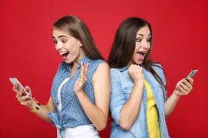 2 Femmes explosent de joie devant leurs smartphones, ravies du forfait 200 Go de B&You à 7€ et du forfait de 300 Go de Cdiscount Mobile  à 10€
