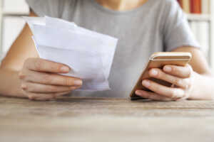 Mains avec factures et smartphone, car hausse de la data et donc des prix sur le marché des forfaits mobile