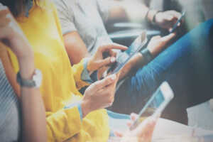 Plusieurs personnes pianotent sur leur smartphone, ravies de leur forfait sur le meilleur réseau mobile de France SFR
