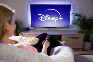 Femme streame Disney+ sur la télé du salon, ravie de la promotion à 2.99€/mois pendant 3 mois