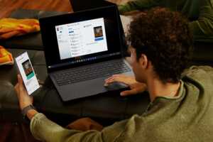 Homme devant PC portable et smartphone, ravi de son duo Bbox Pure Fibre + forfait 130 Go chez B&YOU