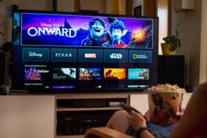 Interface Disney+ sur TV  du salon et pop corn sur canapé, car seulement 1€ avec Livebox Max