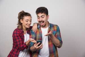 Homme et femme regardent smartphone, heureux et surpris du forfait 50Go de Lebara à moins de 6€