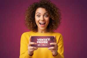 Femme souriante avec smartphone inscrit "Vente Privée", car partenariat entre Ariase et Auchan Télécom pour offre exceptionnelle de 60 Go à moins de 5€